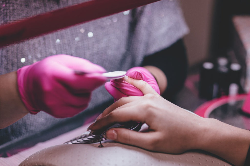 A woman painting a client's nails