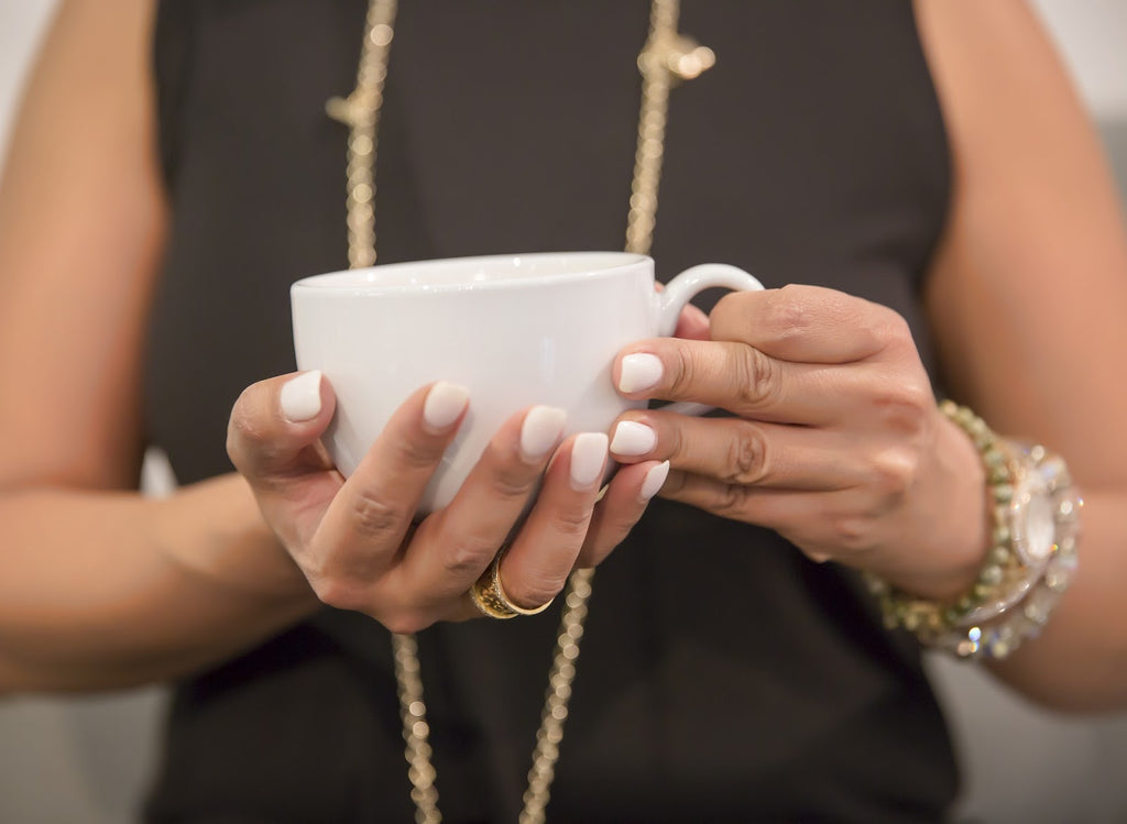A woman with nail polish holding a cup