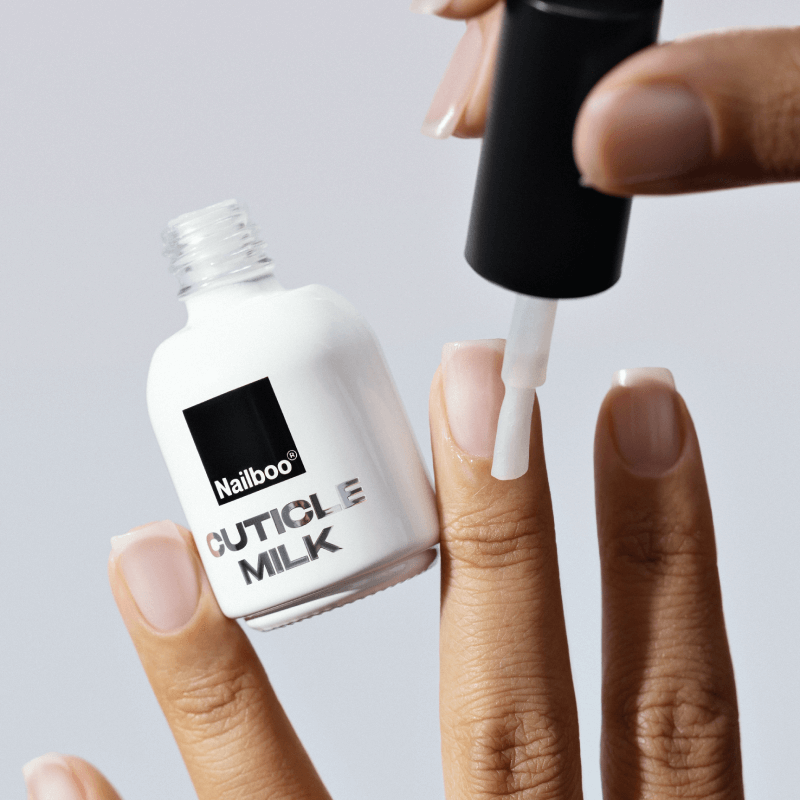 Applying Nailboo Cuticle Milk to fingernails with a brush.