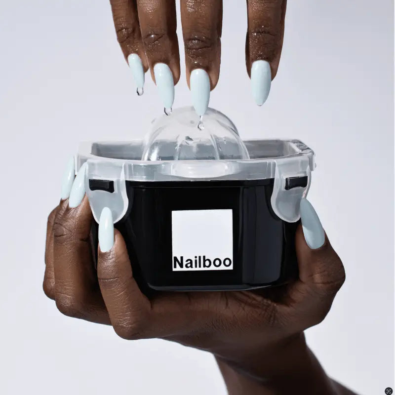 Hands with blue nails using a Nailboo nail kit on a white background.