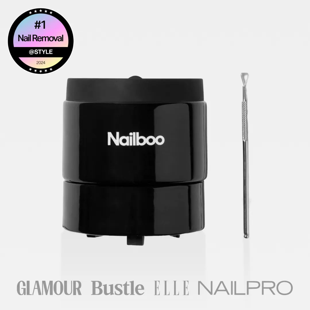 Nailboo manicure set with nail polish bottles, files, cuticle oil, and guidebook against a pink background.