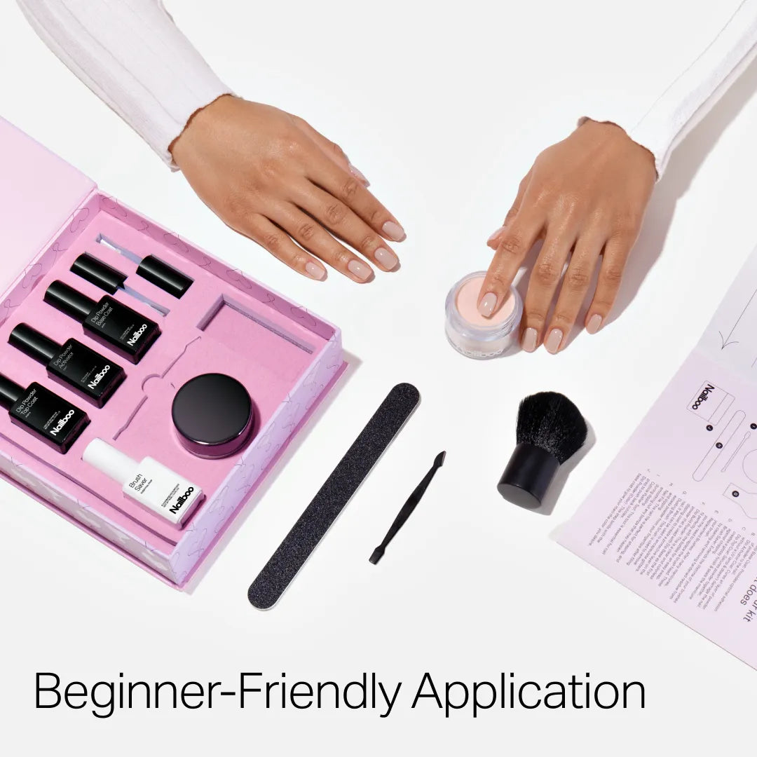 Nailboo manicure set with powders, bottles, and tools against a pink background.