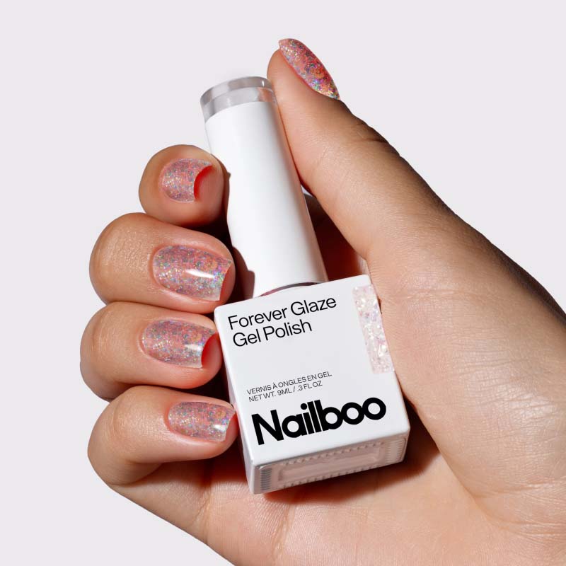 Hand holding a bottle of Nailboo Forever Glaze Gel Polish with sparkly manicured nails.