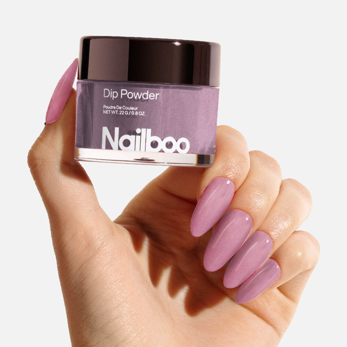 Hand holding a jar of purple Nailboo dip powder with matching manicured nails.